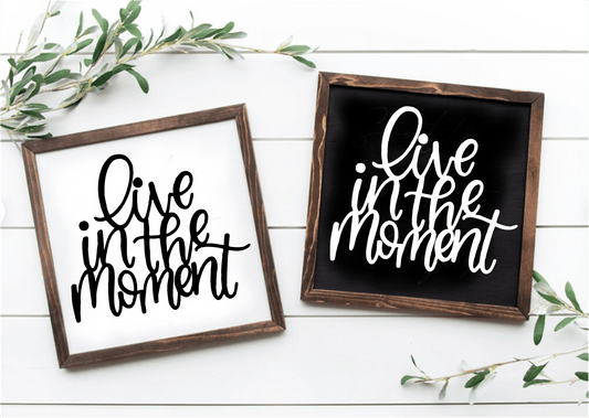Handcrafted framed wood sign with "Live in the Moment" text in black on white and white on black backgrounds.