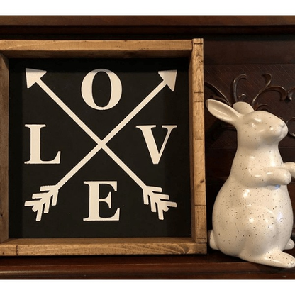 Rustic wood-framed sign with "LOVE" and arrow design on a black background.