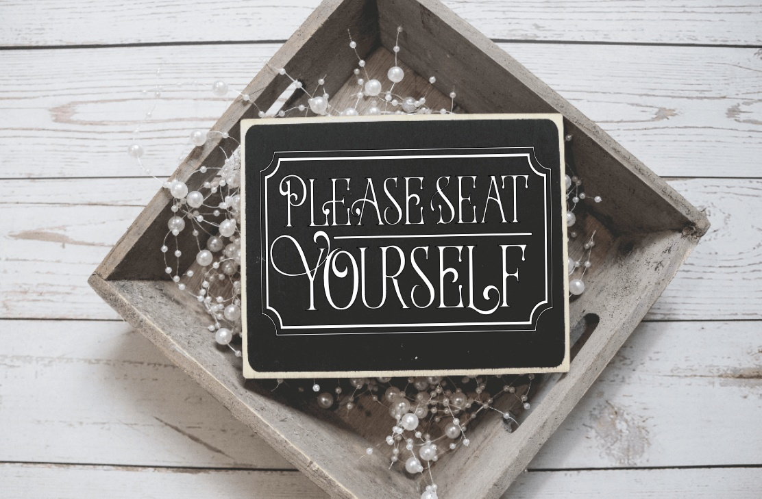Handcrafted wood sign with "Please Seat Yourself" text in a rustic frame.