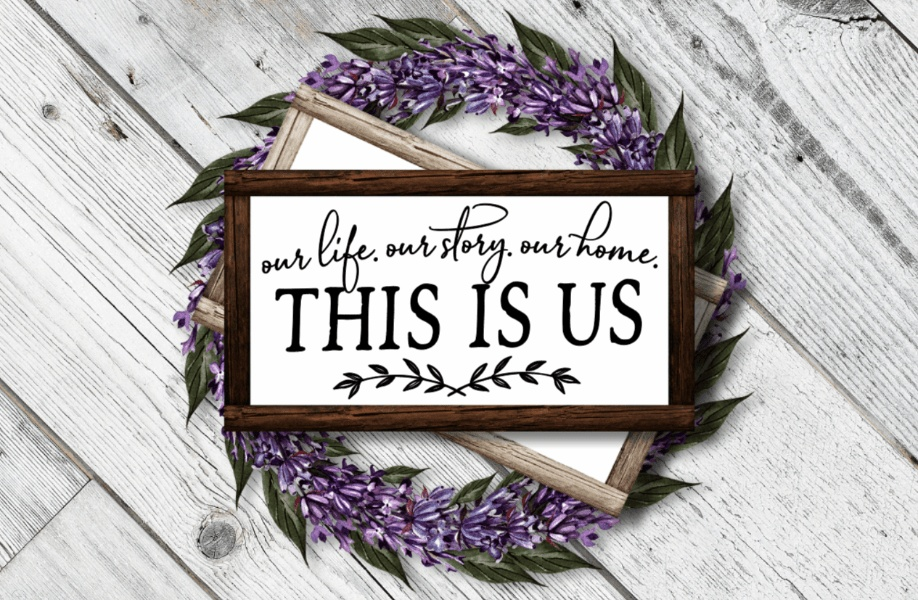 Framed farmhouse wood sign with "This is Us" lettering, stained frame, lavender wreath, white background.