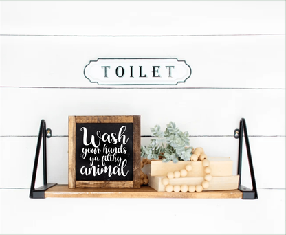 Funny "Wash Your Hands Ya Filthy Animal" framed wood sign on bathroom shelf.