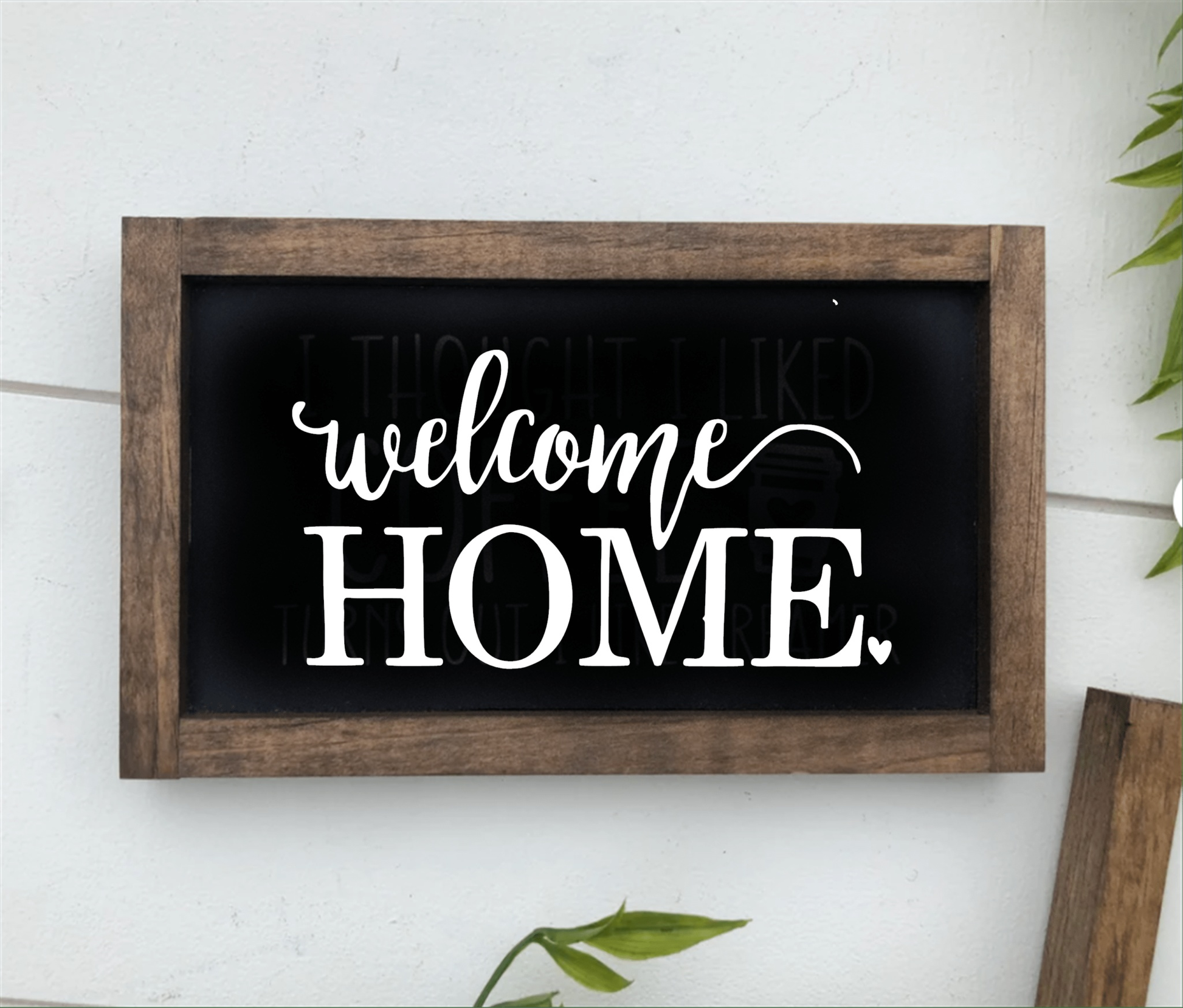 Handmade wooden "Welcome Home" sign with dark frame and white lettering.