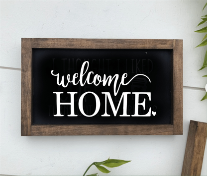 Handmade wooden "Welcome Home" sign with dark frame and white lettering.