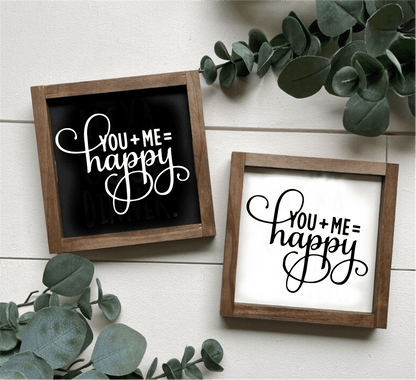 Handcrafted "You Plus Me Equals Happy" wood sign with black and white options, framed and decorated with greenery.