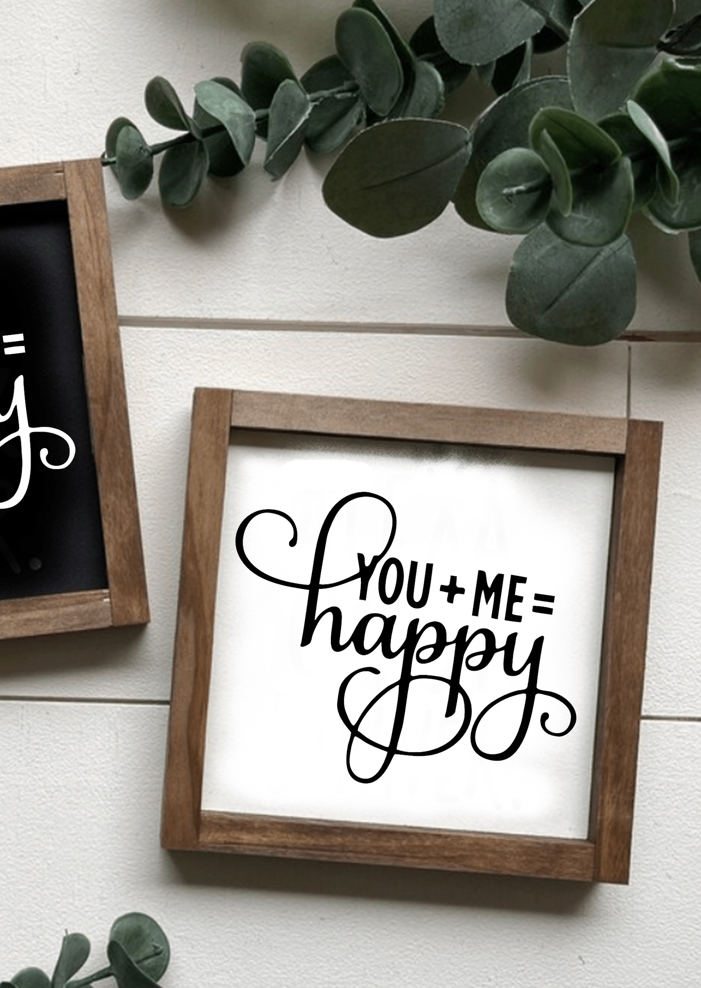 Handcrafted wood sign with "You + Me = Happy" in black lettering on a white background surrounded by a natural wood frame.