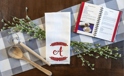 Personalized initial and leaf border tea towel with red letter "A" on table setting.