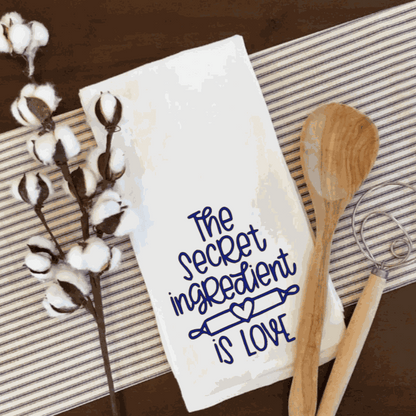 White waffle tea towel with "The secret ingredient is love" design, perfect kitchen accessory.