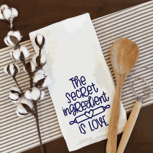 White waffle tea towel with "The secret ingredient is love" design, perfect kitchen accessory.