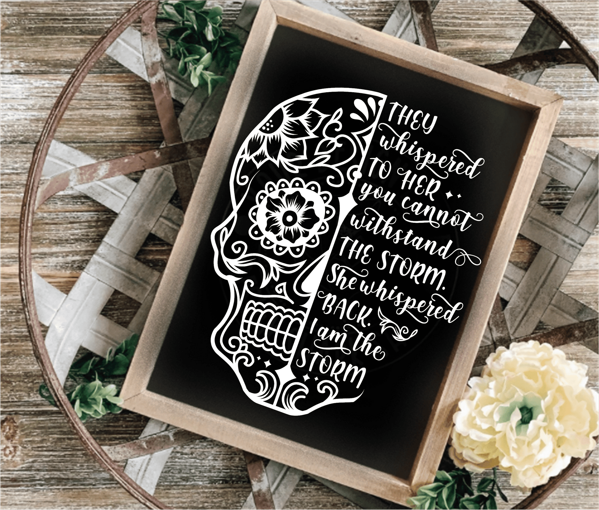 Inspirational wood frame sign with floral skull design and motivational quote on black background.