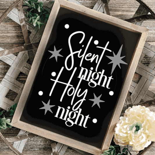 "Silent Night, Holy Night" framed wood sign with black background, white lettering, and silver stars on a rustic surface.